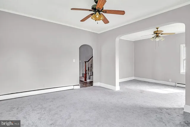 an empty room with a chandelier fan and windows