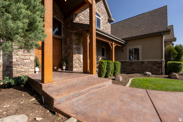687 South 2080th Street East Springville, UT 84663 - Photo 122 of 149 Stone and stucco exterior featuring a prominent covered entry with wood structural columns and a solid wood front door