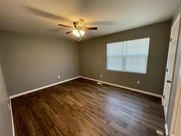 an empty room with wooden floor fan and window
