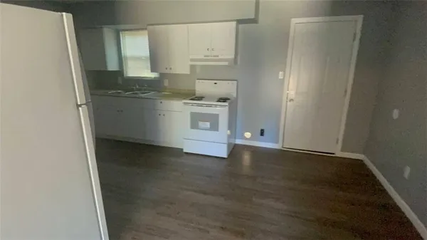 a view of a kitchen with white cabinets and wooden floor
