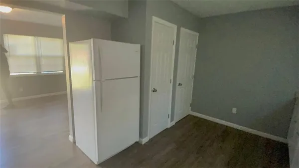 a view of a refrigerator in kitchen and an empty room