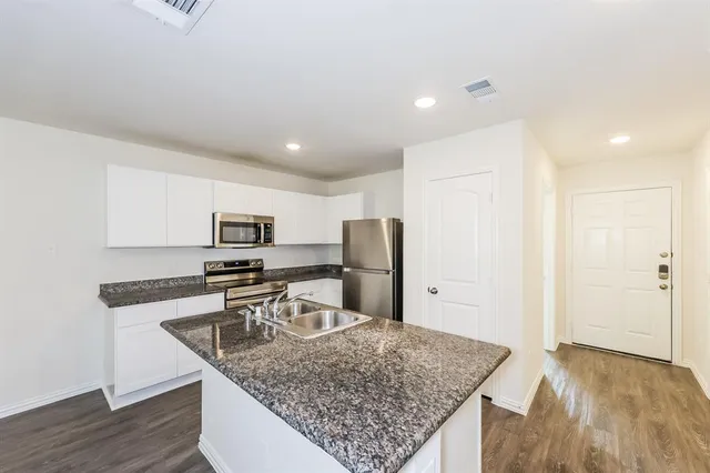 a kitchen with stainless steel appliances granite countertop a sink refrigerator and microwave