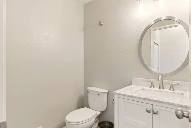 a bathroom with a granite countertop toilet sink and mirror