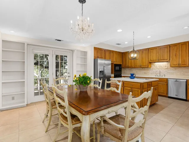 a kitchen with a dining table chairs and refrigerator