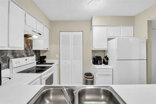 a kitchen with a refrigerator sink and white cabinets