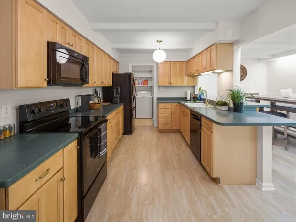 a kitchen with stainless steel appliances granite countertop a stove top oven a sink dishwasher a refrigerator and a dining table with wooden floor