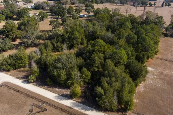 an aerial view of residential house with outdoor space and trees all around