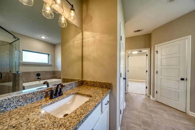 a bathroom with a granite countertop sink a mirror and a shower