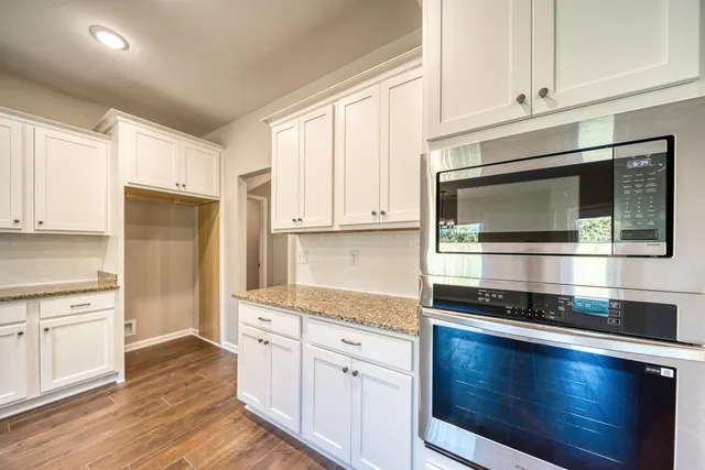 a kitchen with stainless steel appliances granite countertop a stove a microwave and white cabinets