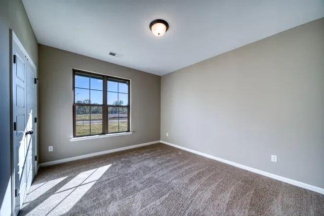 a view of an empty room with a window and a kitchen