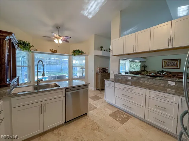 a kitchen with stainless steel appliances a refrigerator a sink and white cabinets