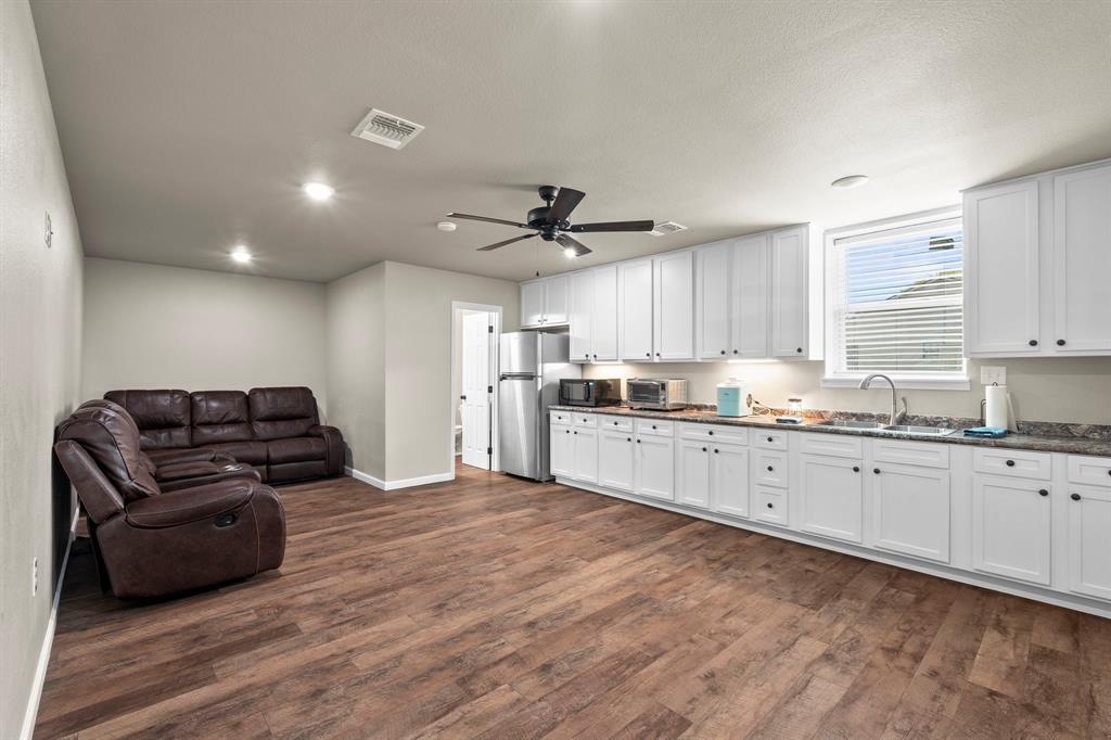 1404 McConnell Road Gunter, TX 75058 - Photo 8 of 27 a kitchen with granite countertop a refrigerator oven a sink dishwasher and white cabinets with wooden floor