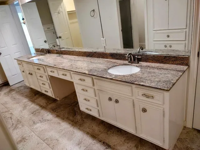 a bathroom with a granite countertop sink and a mirror