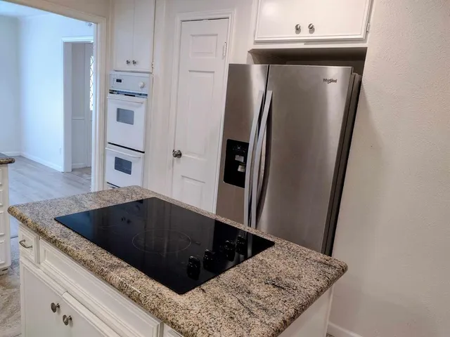 a view of kitchen island with stainless steel appliances wooden floor