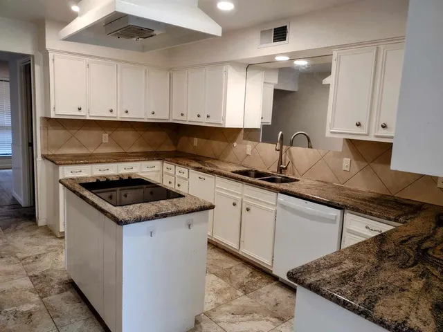 a kitchen with granite countertop a sink a stove and cabinets