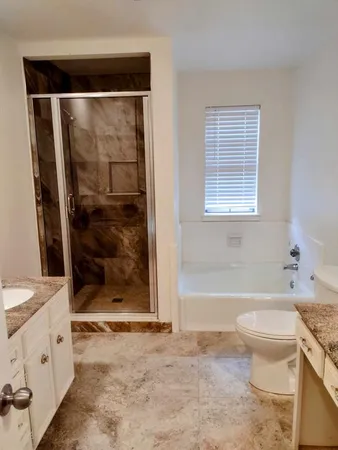 a bathroom with a granite countertop sink a toilet and shower
