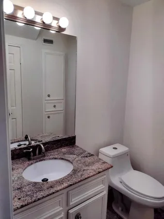 a bathroom with a granite countertop sink and a toilet
