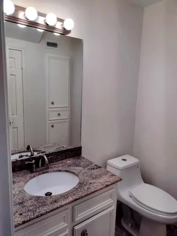 a bathroom with a granite countertop sink and a toilet