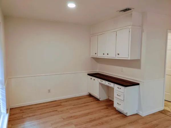 a room with wooden floor and white cabinets