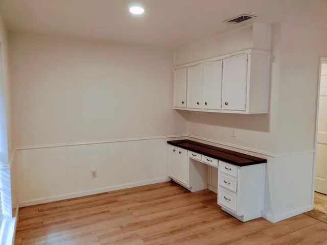 a room with wooden floor and white cabinets