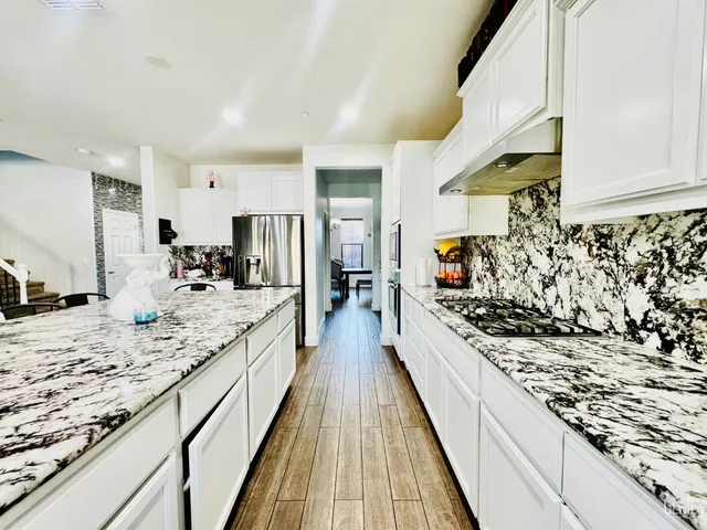a large kitchen with kitchen island granite countertop a large counter top and wooden floors