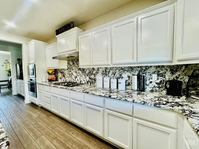a kitchen with granite countertop a sink stainless steel appliances and white cabinets