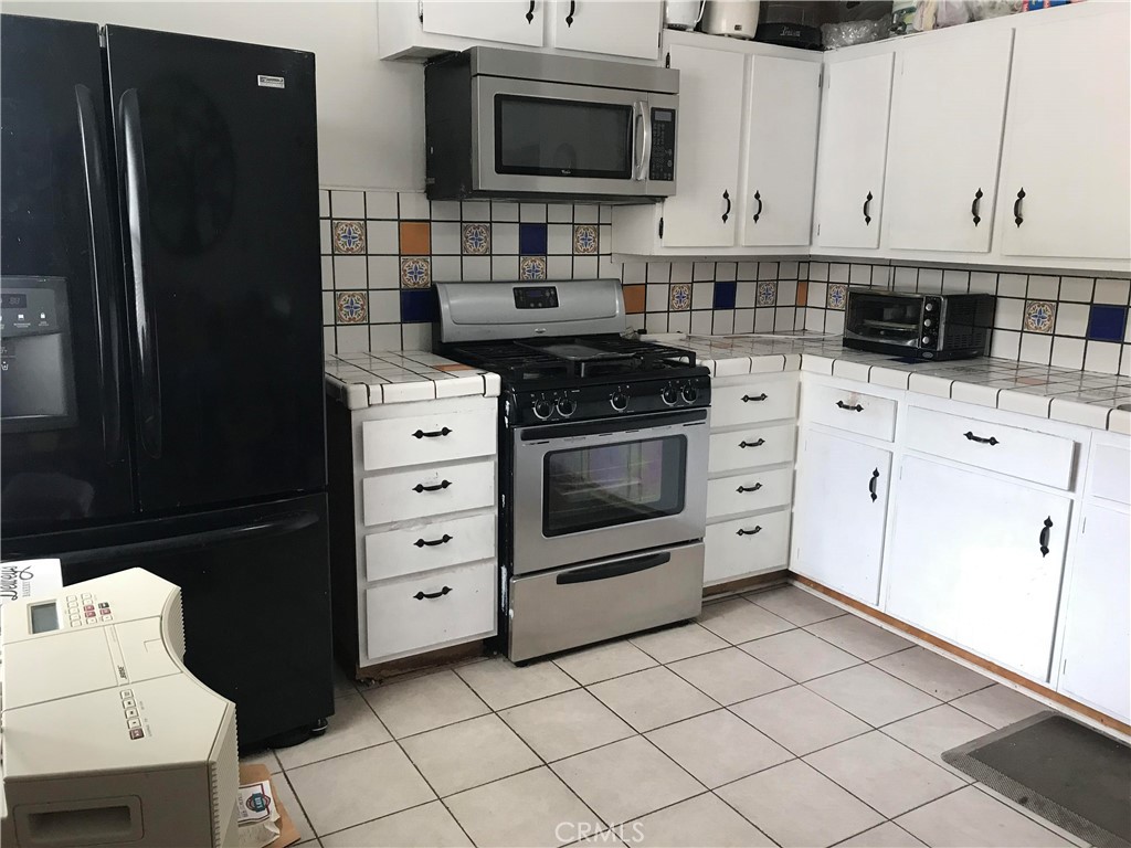 1363 Walnut Canyon Road Moorpark, CA 93021 - Photo 4 of 7 a kitchen with a refrigerator stove and white cabinets