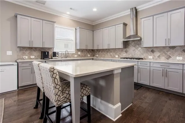 a kitchen with stainless steel appliances granite countertop a white cabinets sink a stove a dining table and chairs