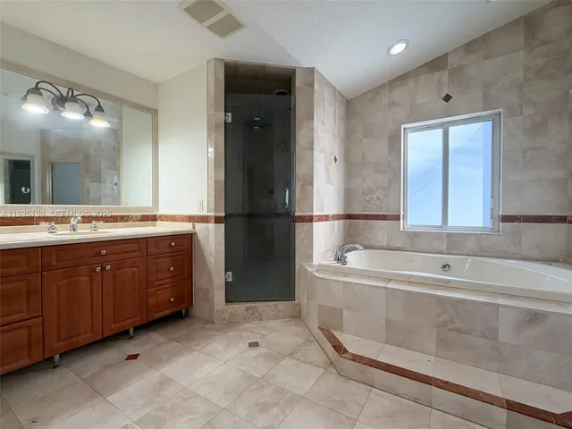 a spacious bathroom with a tub sink and a mirror