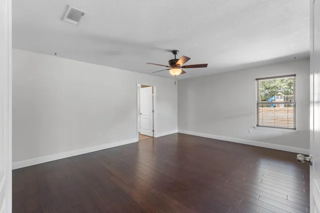 a view of an empty room with wooden floor and window