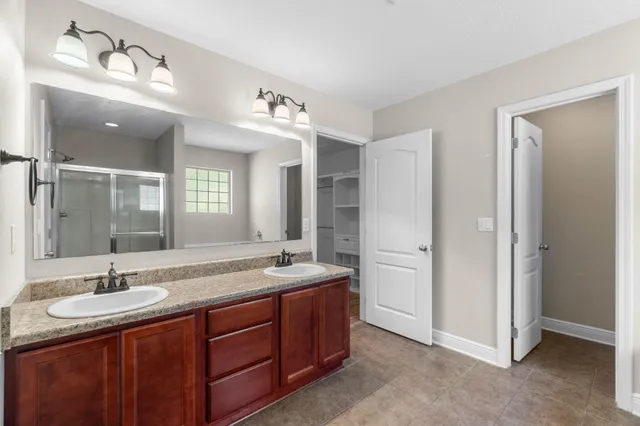 a bathroom with a granite countertop double vanity sink and mirror