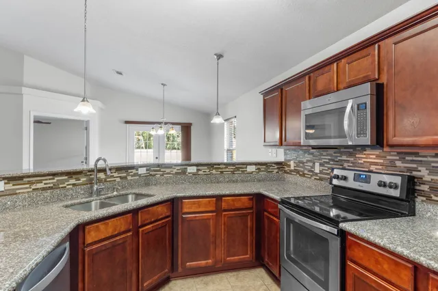 a kitchen with stainless steel appliances granite countertop a sink stove and microwave