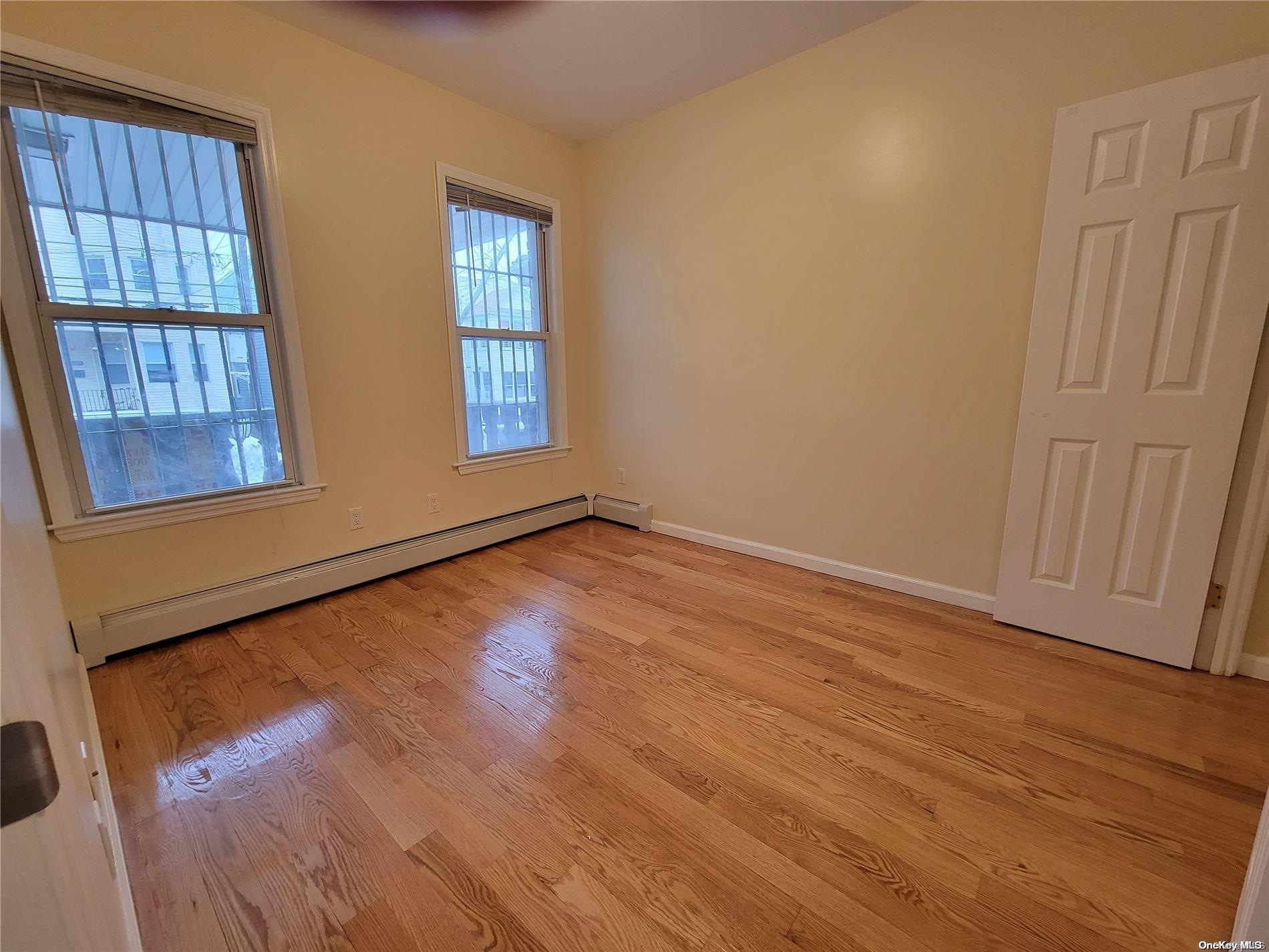 85-30 79th Street Queens, NY 11421 - Photo 11 of 23 an empty room with wooden floor and windows
