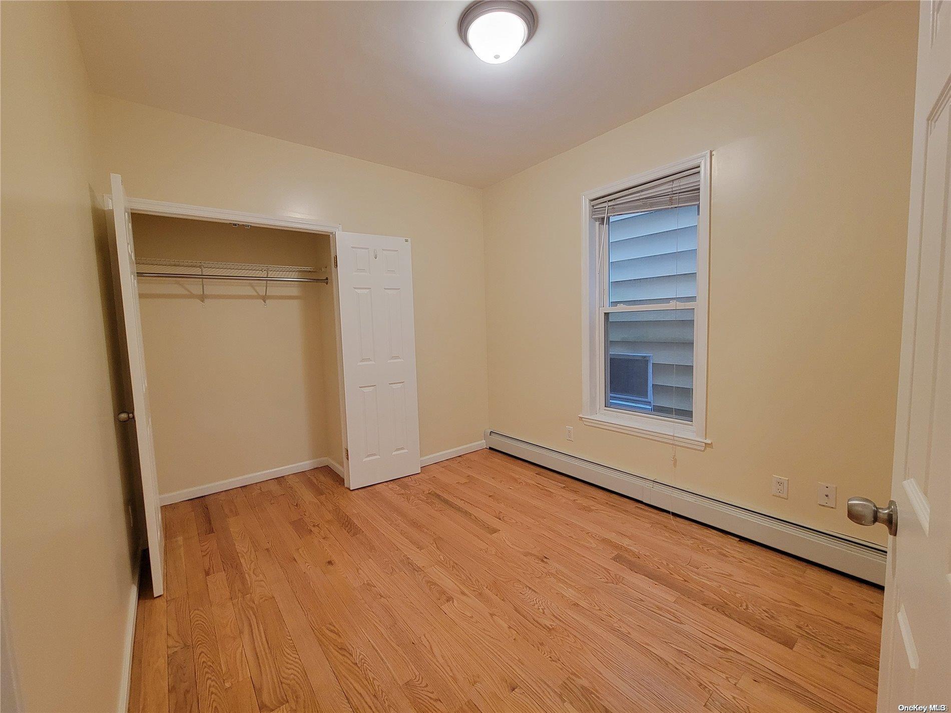 85-30 79th Street Queens, NY 11421 - Photo 12 of 23 a view of an empty room with wooden floor and a window
