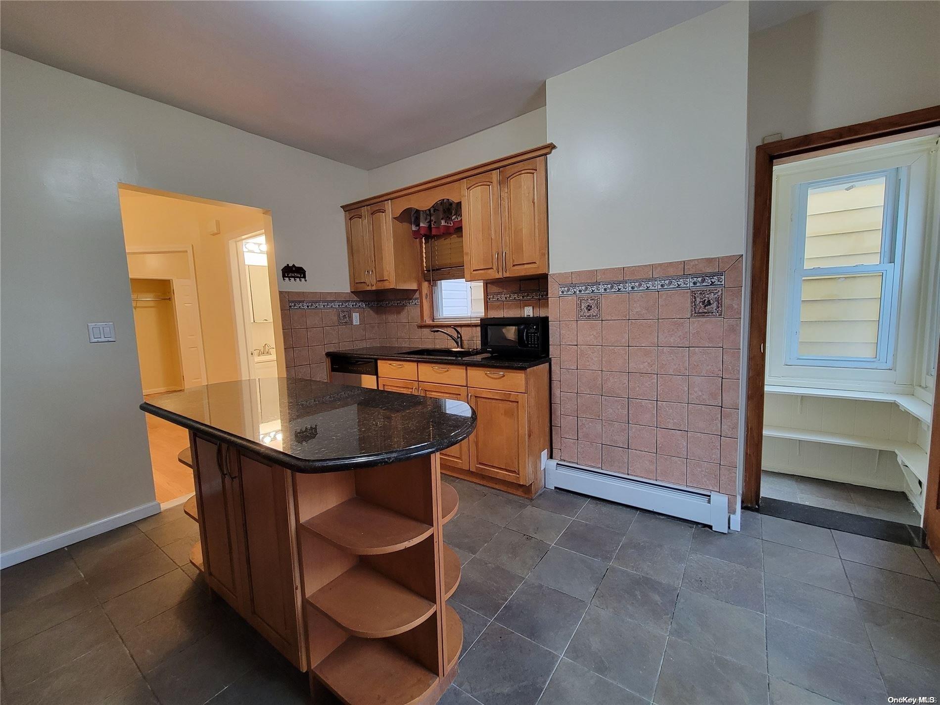 85-30 79th Street Queens, NY 11421 - Photo 16 of 23 a kitchen that has a kitchen island wooden cabinets and stainless steel appliances