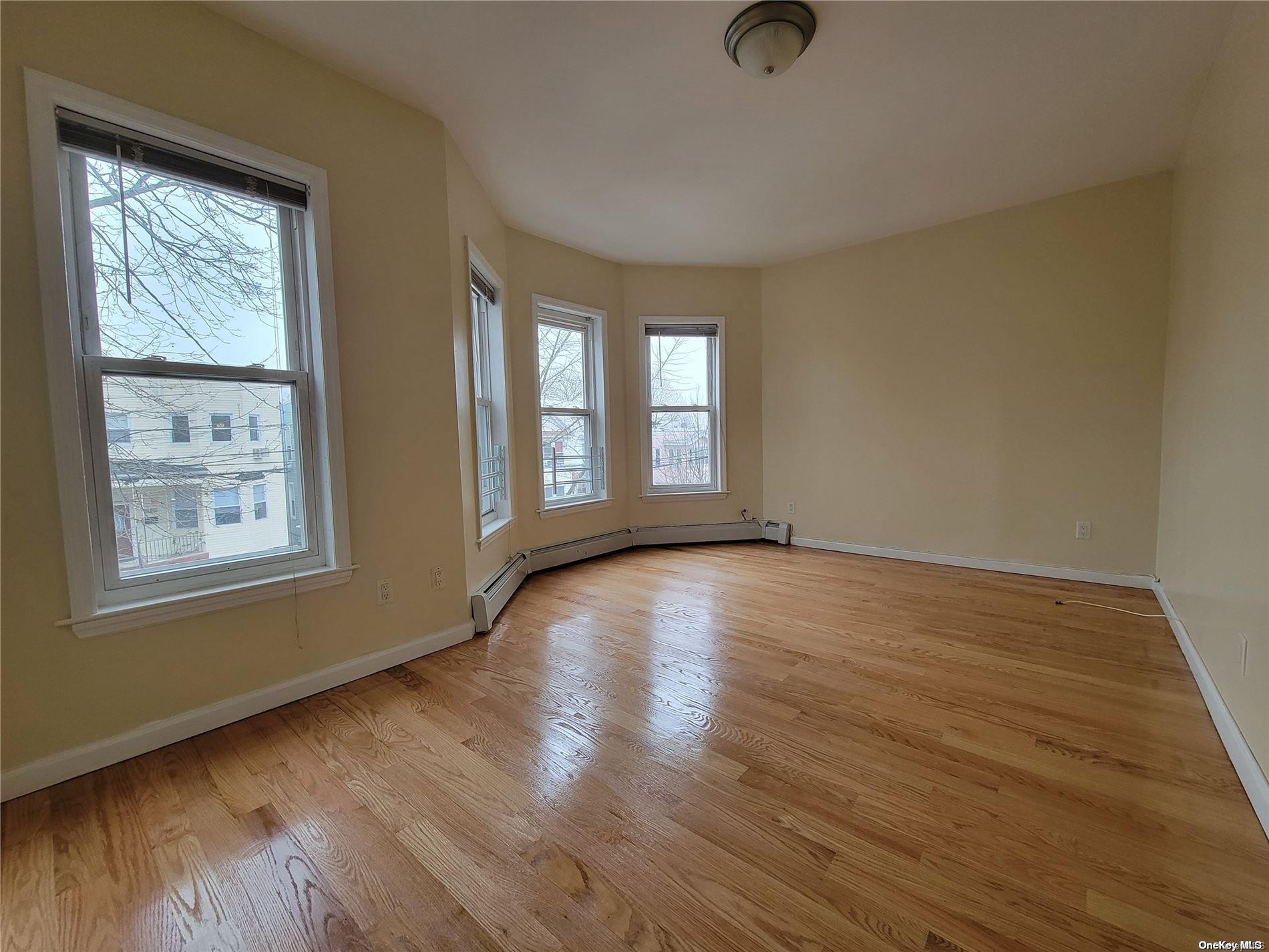 85-30 79th Street Queens, NY 11421 - Photo 5 of 23 a view of an empty room with wooden floor and a window