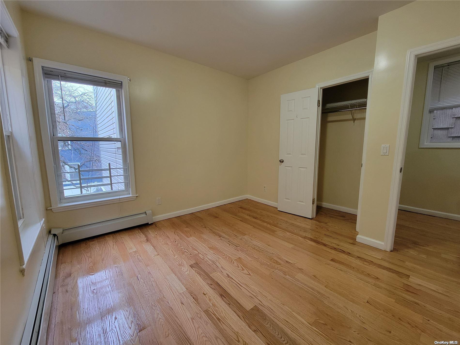 85-30 79th Street Queens, NY 11421 - Photo 8 of 23 an empty room with wooden floor and windows