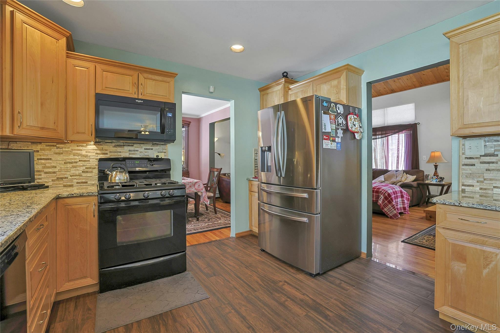31 Powder Horn Road Cortlandt Manor, NY 10567 - Photo 6 of 36 Kitchen with light stone countertops, decorative backsplash, black appliances, dark wood-style floors, and recessed lighting