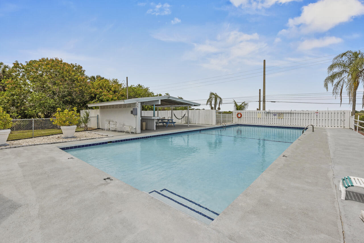 14601 Orange Avenue Fort Pierce, FL 34945 - Photo 22 of 37 a view of a swimming pool with a lawn chairs under an umbrella