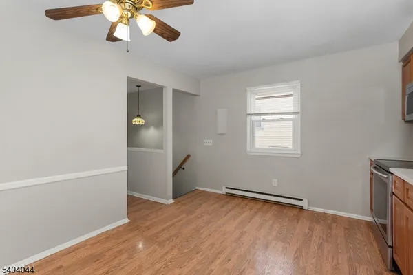 an empty room with wooden floor fan and windows