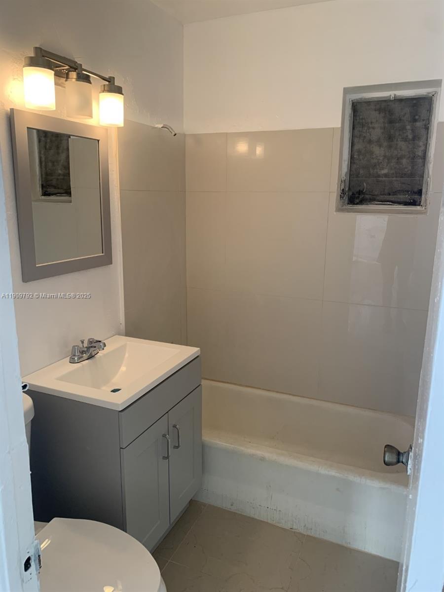 2181 Northwest 91st Street Miami, FL 33147 - Photo 7 of 14 a bathroom with a toilet a sink a mirror and a bathtub