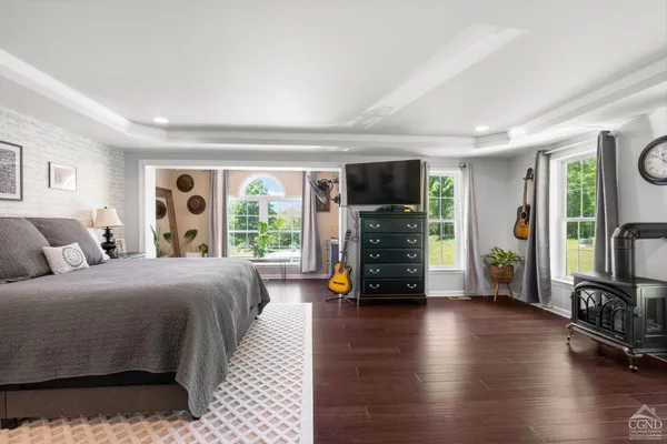 a bedroom with a bed a large window and wooden floor