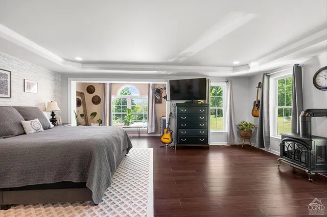 a bedroom with a bed a large window and wooden floor
