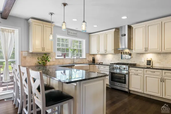a kitchen with stainless steel appliances granite countertop a stove a sink dishwasher a dining table and chairs with wooden floor