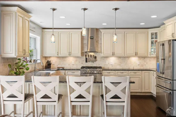 a kitchen with stainless steel appliances granite countertop a stove top oven a refrigerator a sink and white cabinets