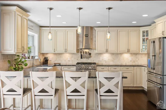 a kitchen with stainless steel appliances granite countertop a stove top oven a refrigerator a sink and white cabinets