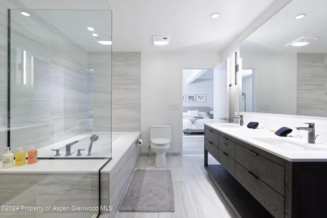 a bathroom with a double vanity sink mirror and bathtub