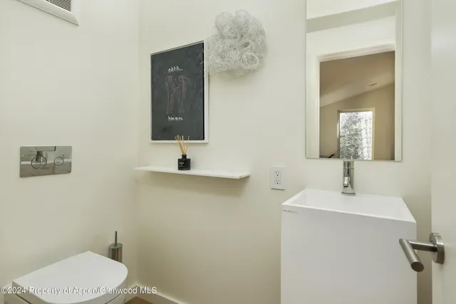 a bathroom with a toilet sink and mirror