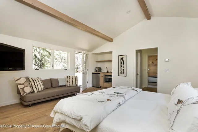 a spacious bedroom with a bed and a flat screen tv