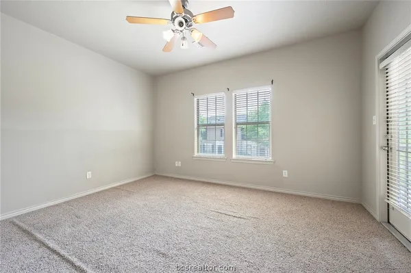 an empty room with a window and a ceiling fan
